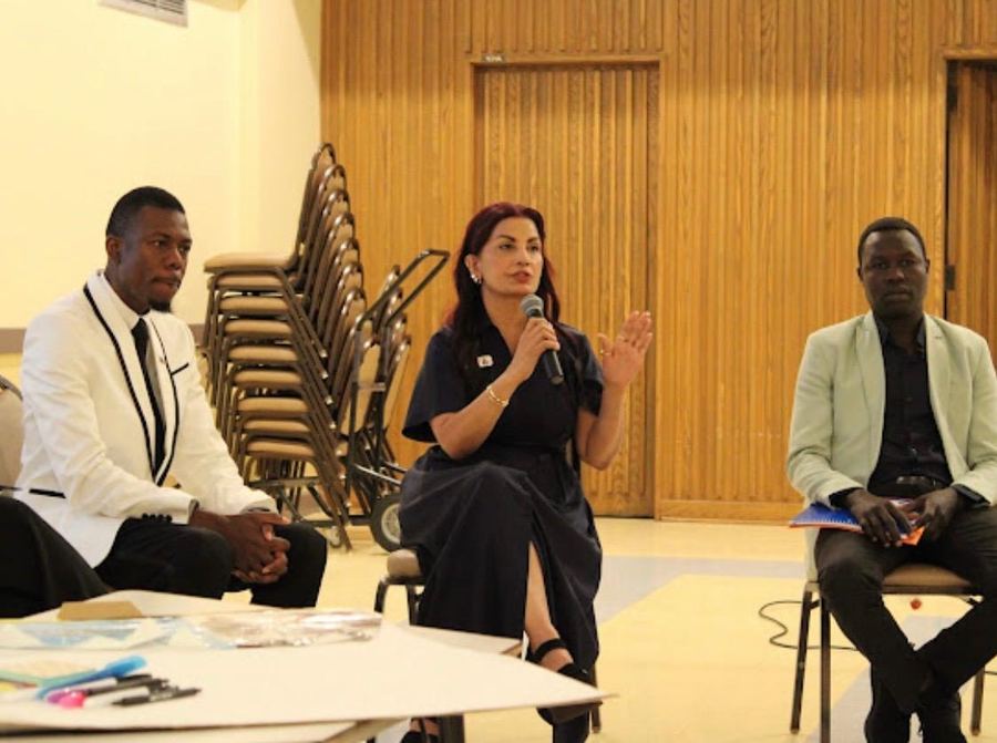 Dr. Samira Khan speaking into a microphone on a panel at a community forum