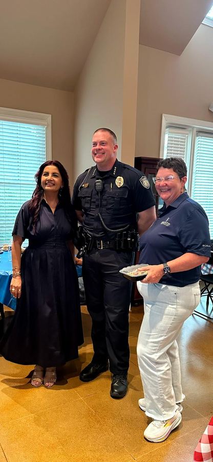 Dr. Samira Khan with a uniformed police officer and a community member at an indoor community event
